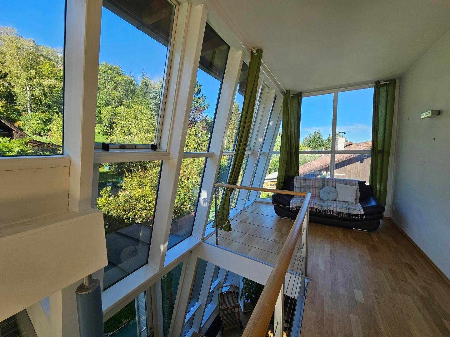 Galeriebereich mit Sitzgelegenheit, Holzfußboden und beeindruckenden Ausblicken durch die Fensterfront.