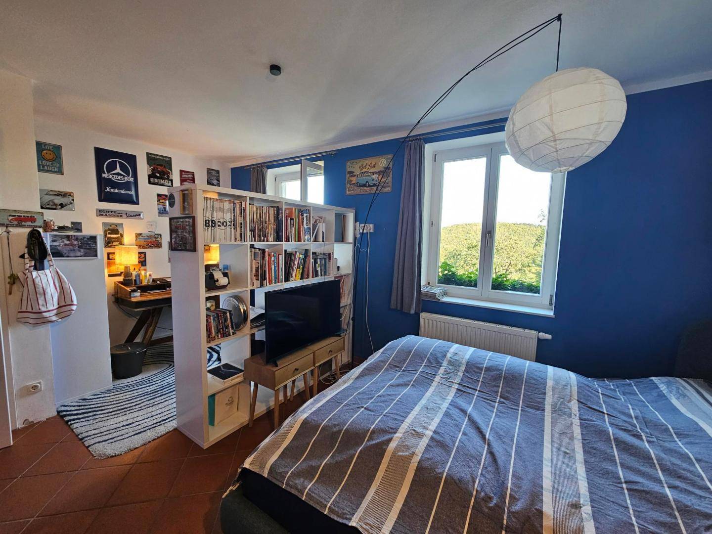 Schlafzimmer mit blauen Wänden, Terrakottafliesen und einem integrierten Arbeitsbereich.