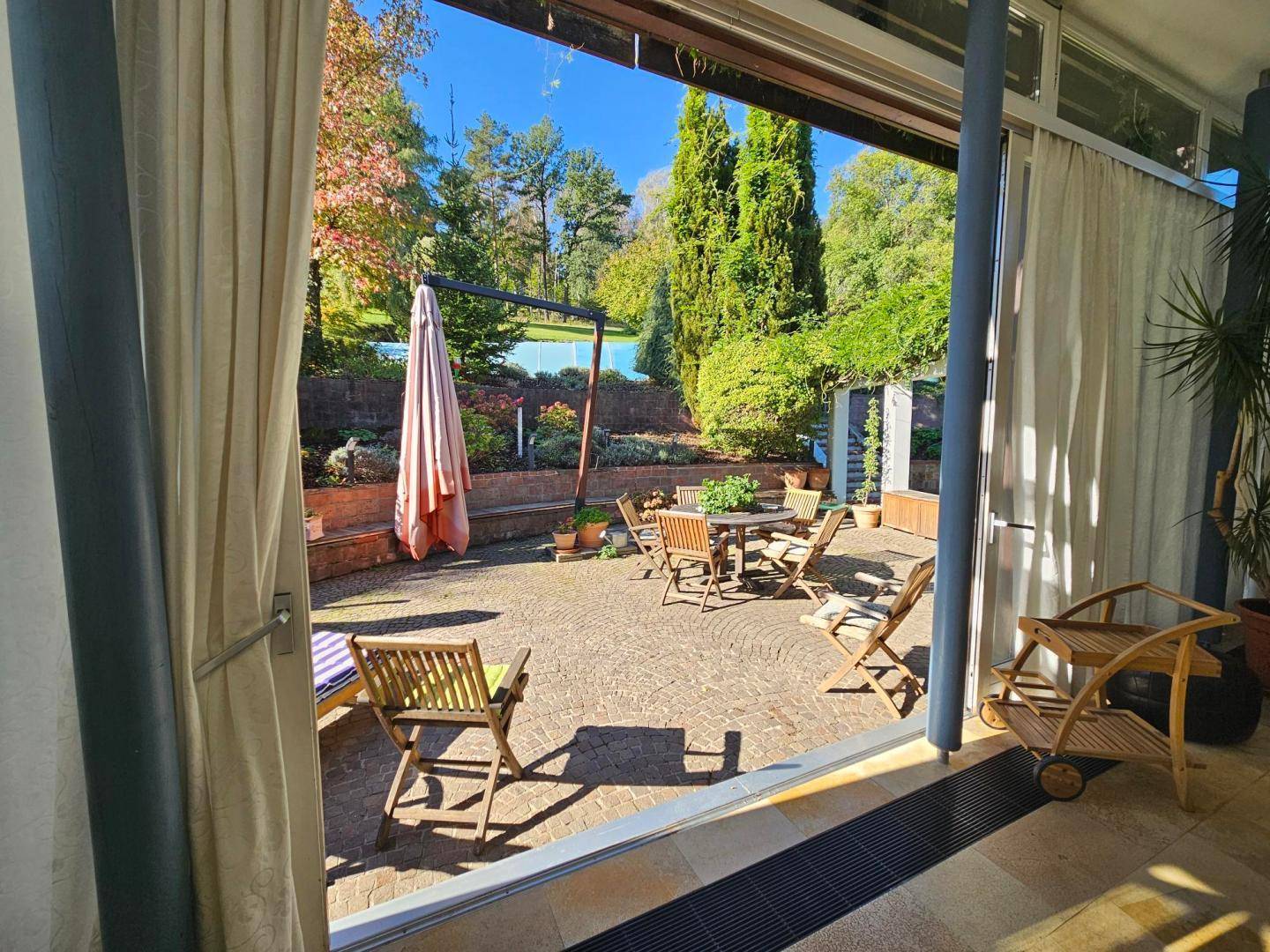 Geräumige gepflasterte Terrasse mit Gartenmöbeln und Blick auf die grüne Umgebung.