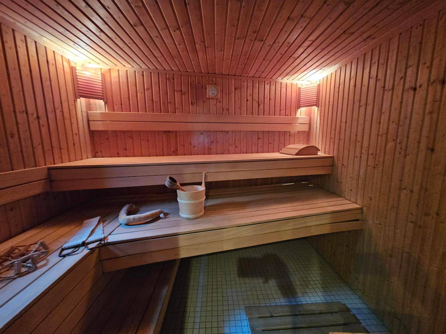 Traditionelle Holzsauna mit mehreren Bänken und typischem Zubehör für Entspannung.