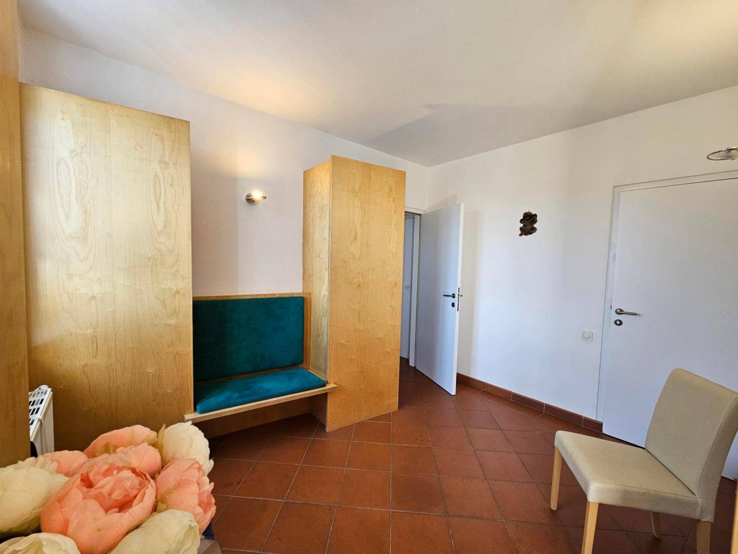 Raum mit Terrakottafliesen und Holztrennwänden, möglicherweise als Ankleide oder Gästezimmer genutzt.