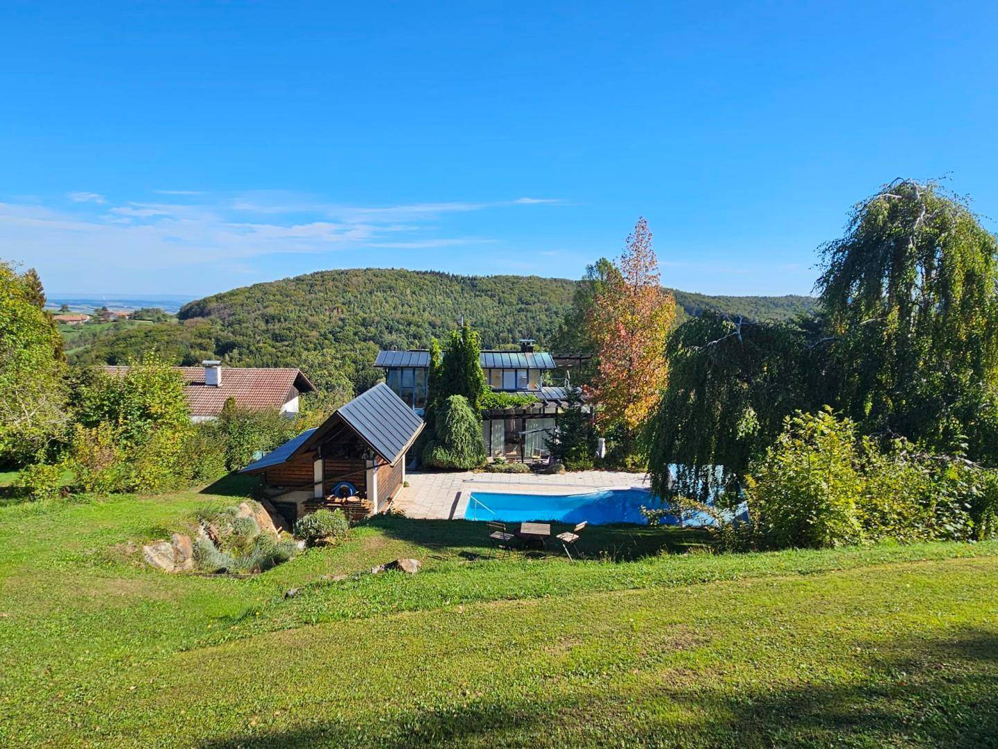 Weitläufiges Anwesen mit Pool, umgeben von grünen Hügeln und einem entfernten Blick auf das Wasser.