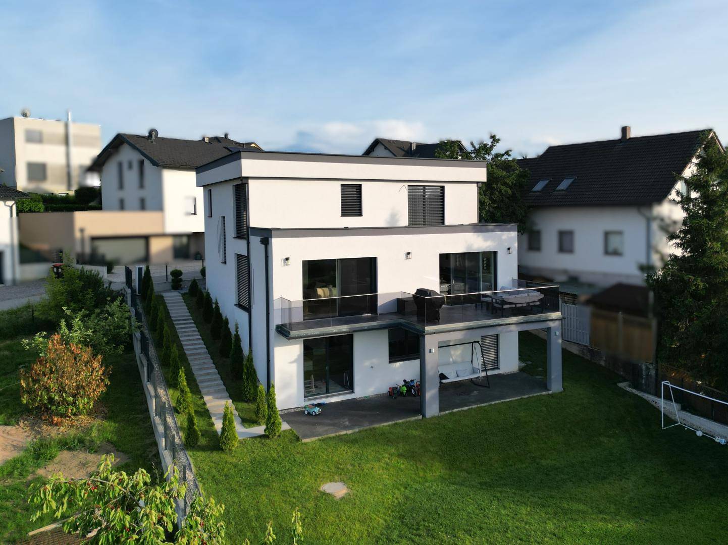 Modernes Einfamilienhaus mit großem Garten, Terrasse und Balkon in ländlicher Umgebung.