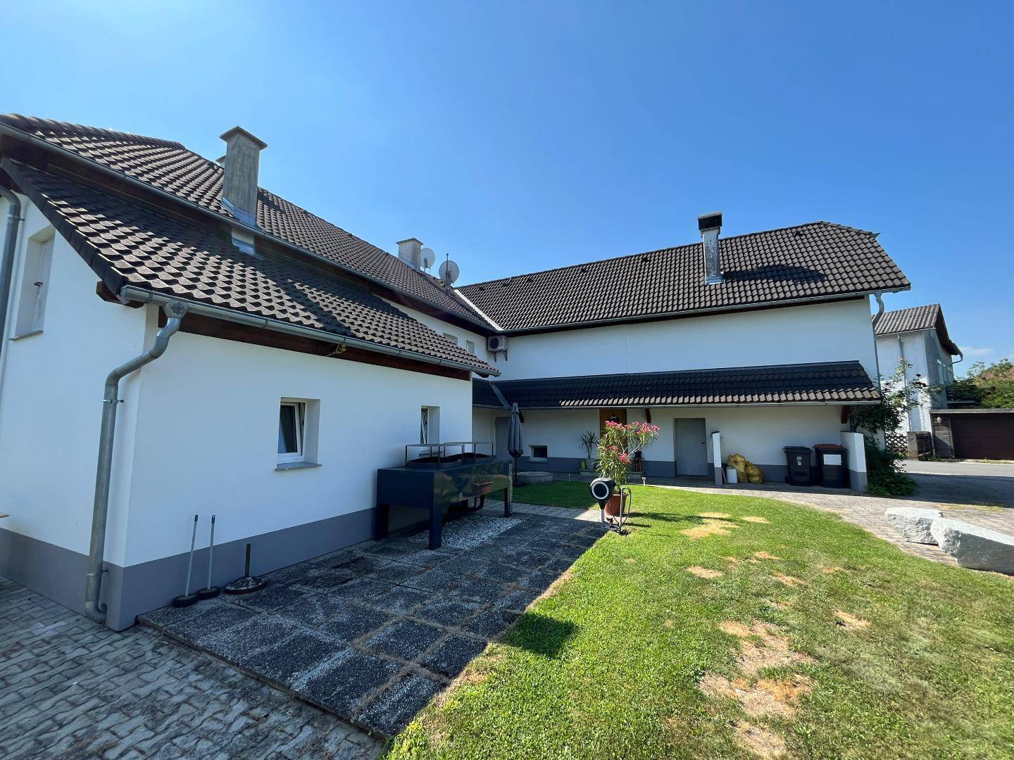 Großer Gartenbereich mit Rasenfläche, gepflastertem Weg und Blick auf das Gebäude.