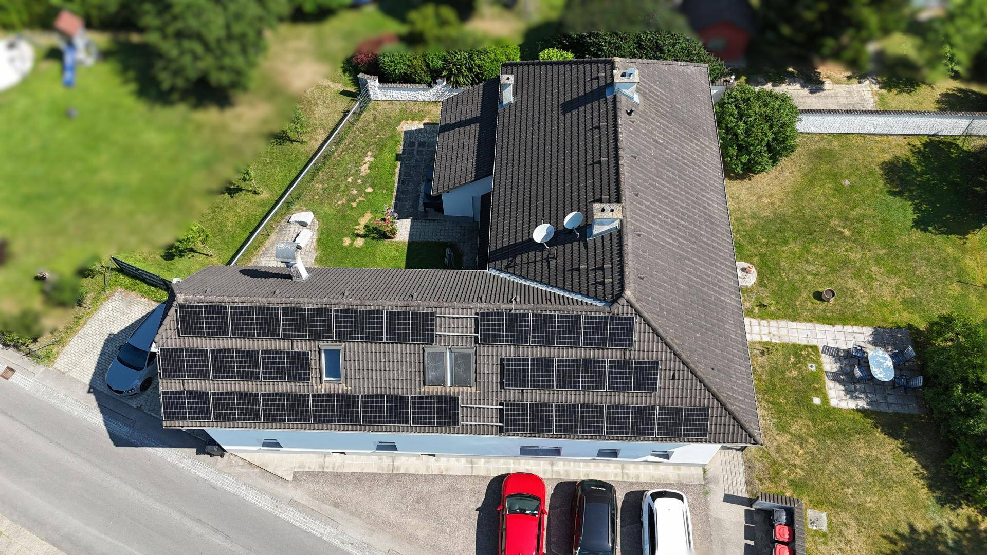 Luftaufnahme des Hauses mit Solaranlage auf dem Dach und Parkplätzen davor.