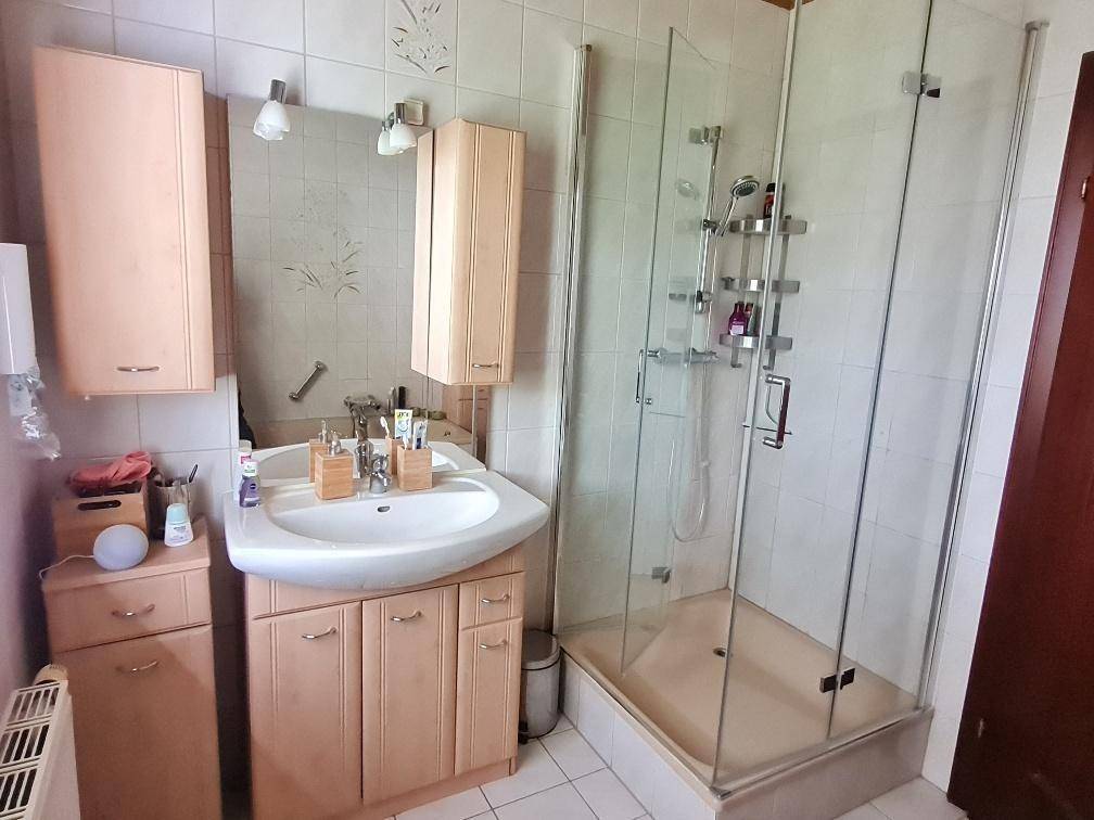 Badezimmer mit Duschkabine, Einzelwaschbecken und hellen Fliesen.