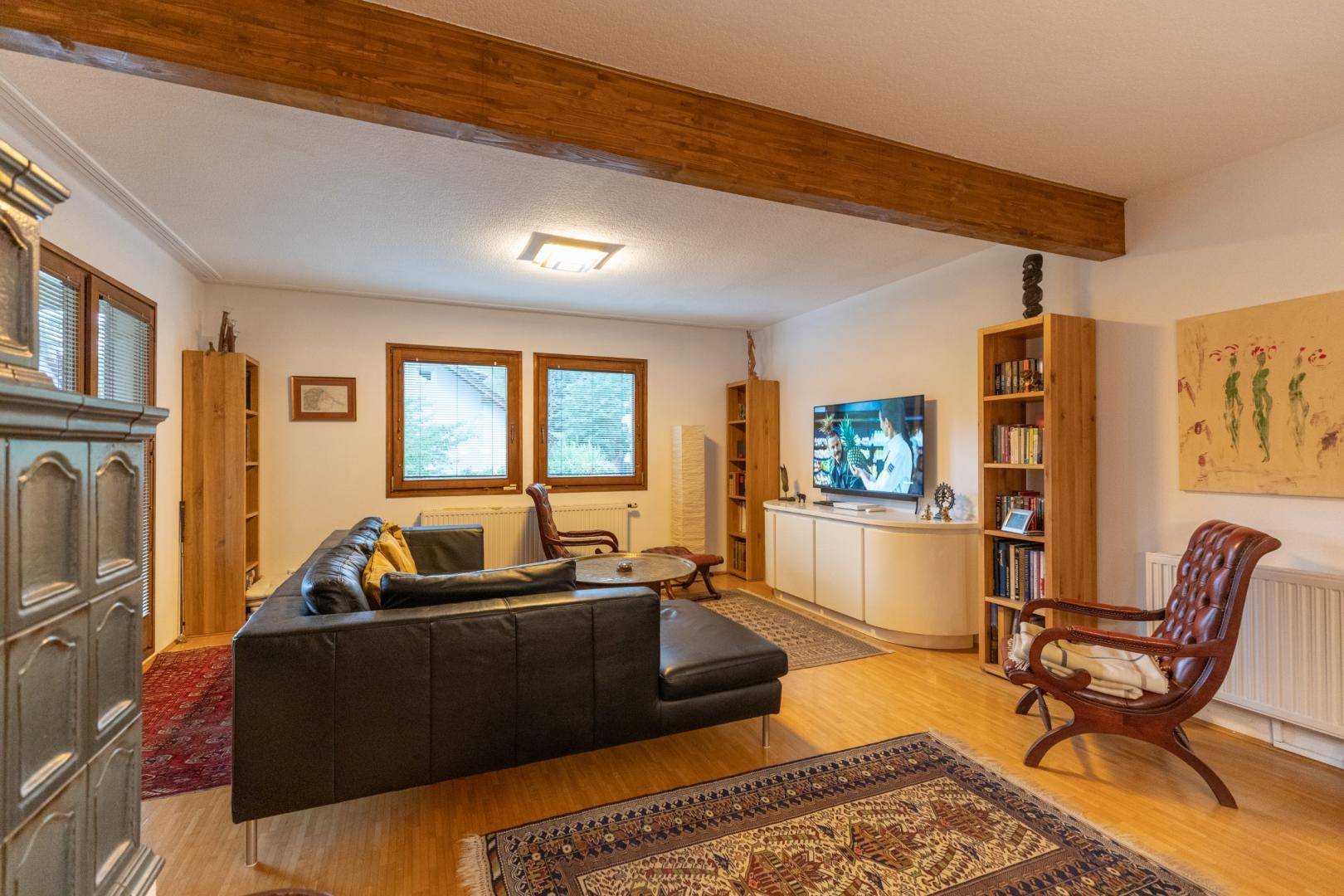 Gemütliches Wohnzimmer mit Holzbalken, Parkettboden und bequemer Ledercouch.
