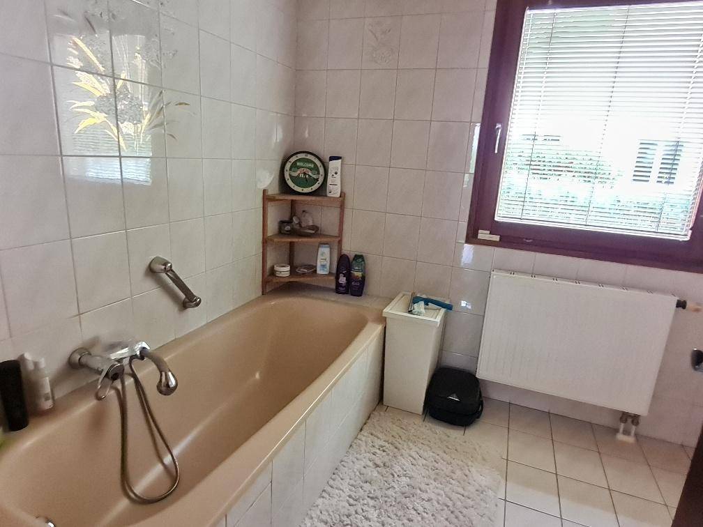 Badezimmer mit Badewanne, Fenster und hellen Fliesen in traditionellem Stil.