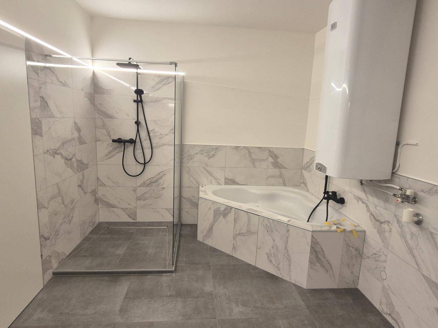 Modernes Badezimmer mit großer begehbarer Dusche, Eckbadewanne und eleganten Marmorfliesen.