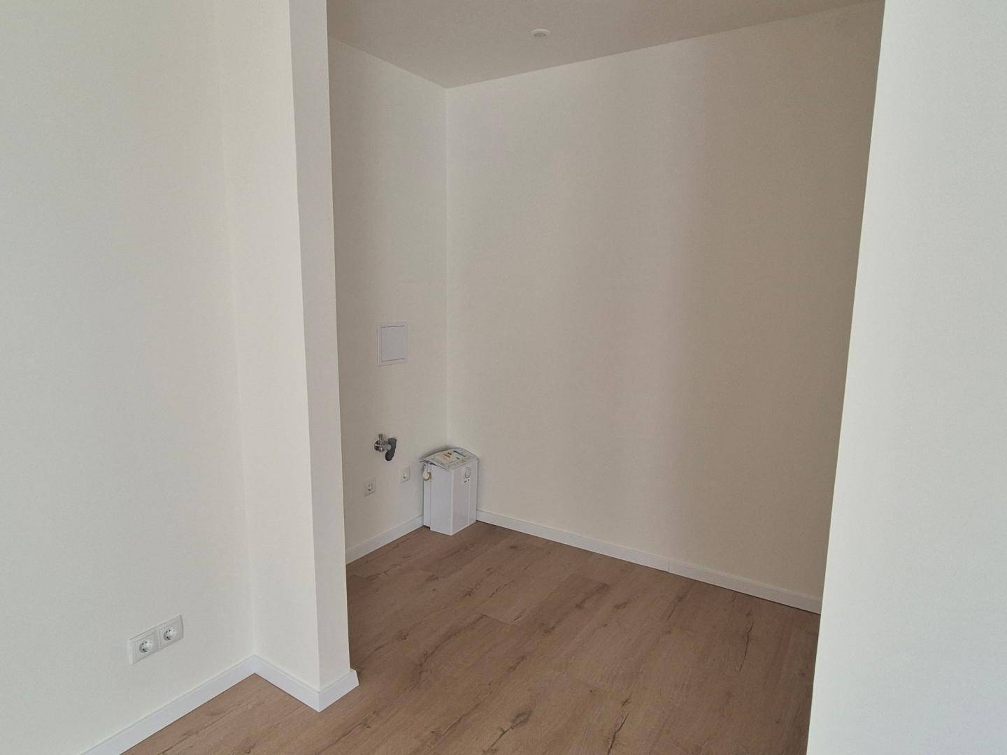 Kleiner Hauswirtschaftsraum mit Anschlüssen für Waschmaschine und hellem Laminatboden.