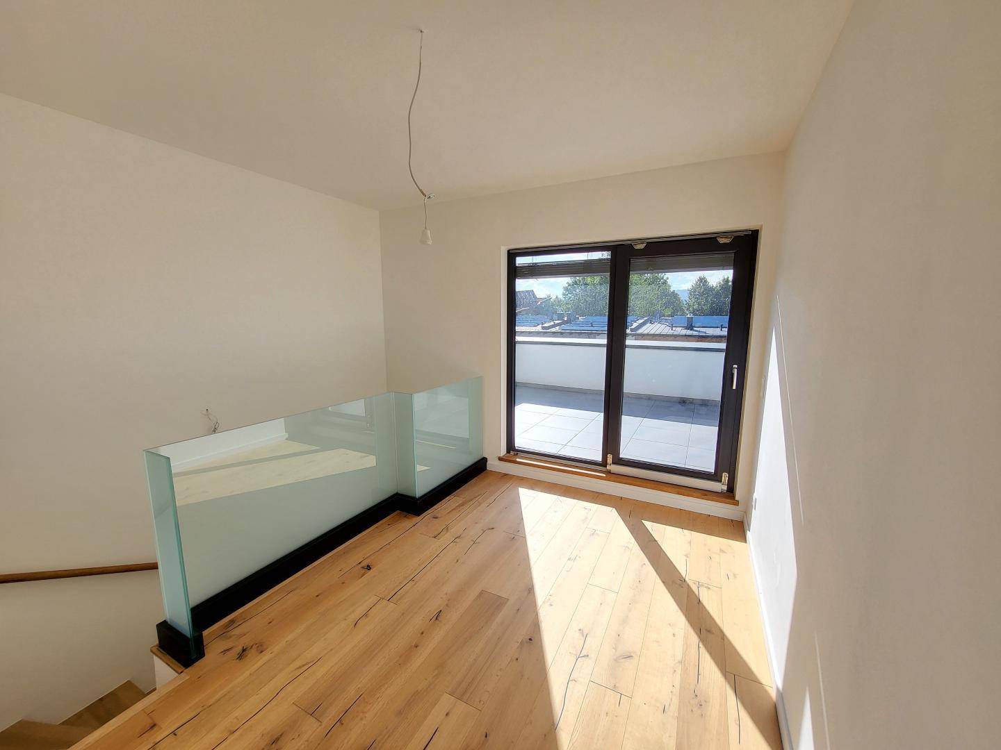 Lichtdurchfluteter Bereich im Obergeschoss mit Holzboden und Zugang zur Dachterrasse.