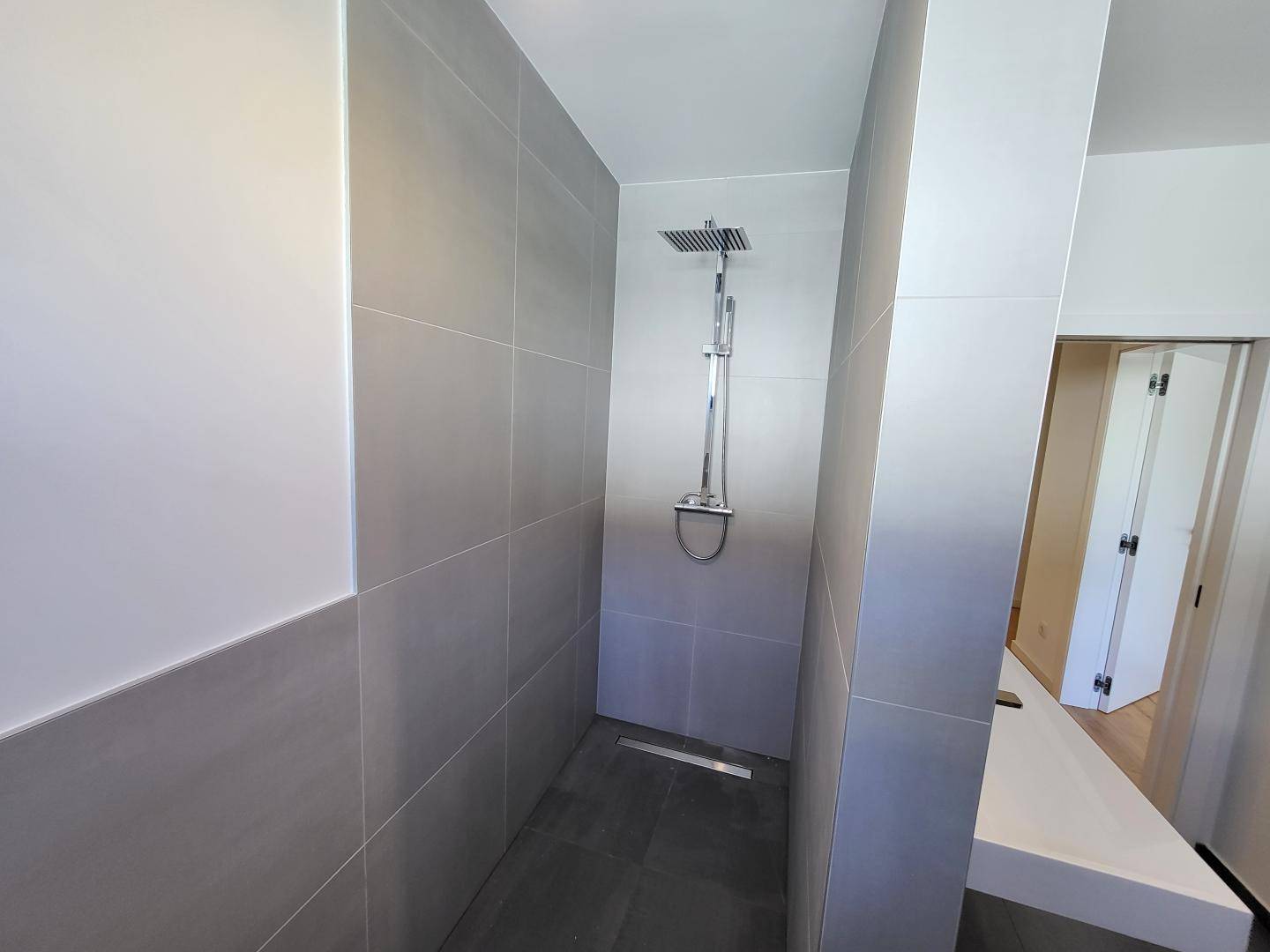 Modernes Badezimmer mit begehbarer Dusche und großformatigen Fliesen.