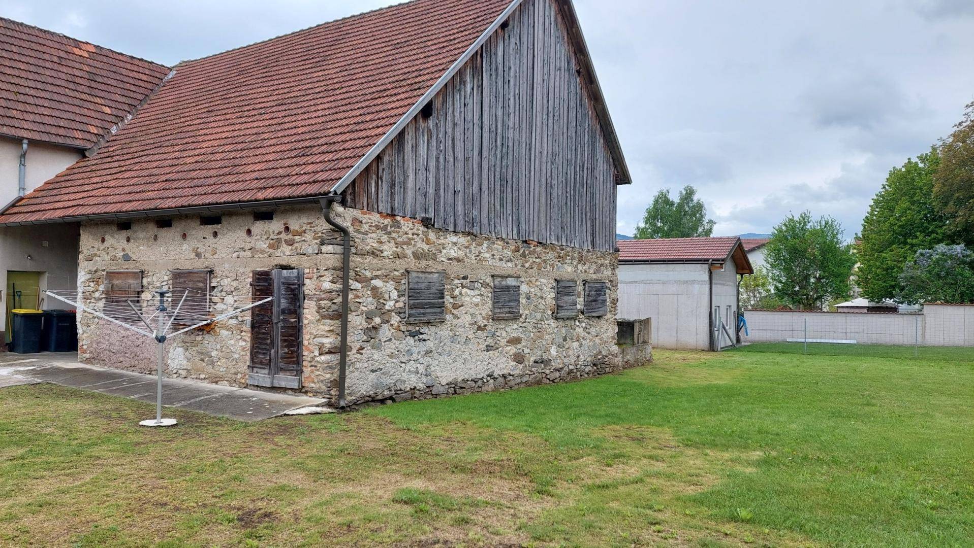 Ansicht des alten Bauernhauses mit Scheune und weitläufigem Rasenbereich im ländlichen Umfeld.