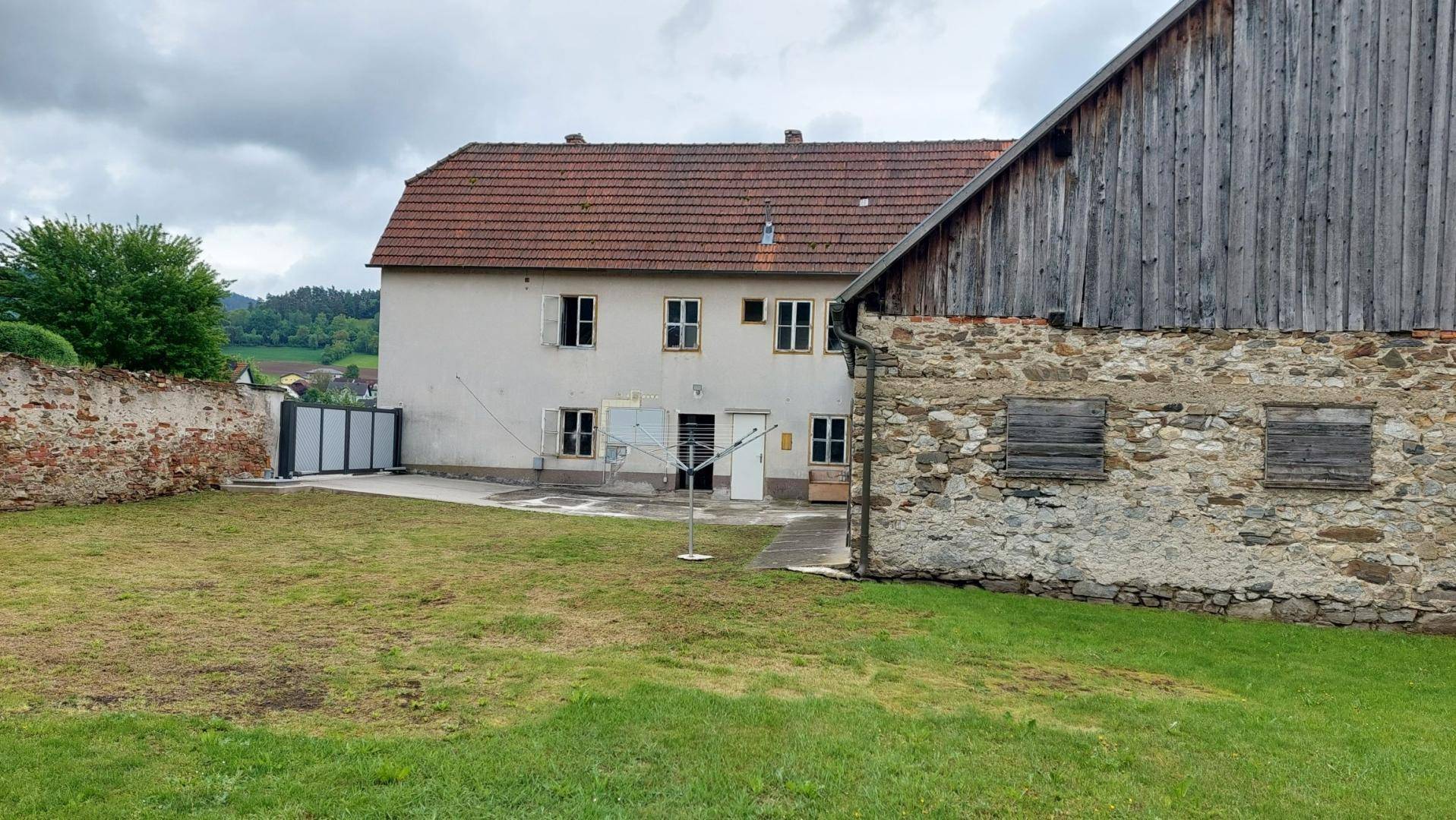 Großer Gartenbereich neben dem historischen Gebäudeensemble mit Scheune und Wohnhaus, umgeben von Natur.