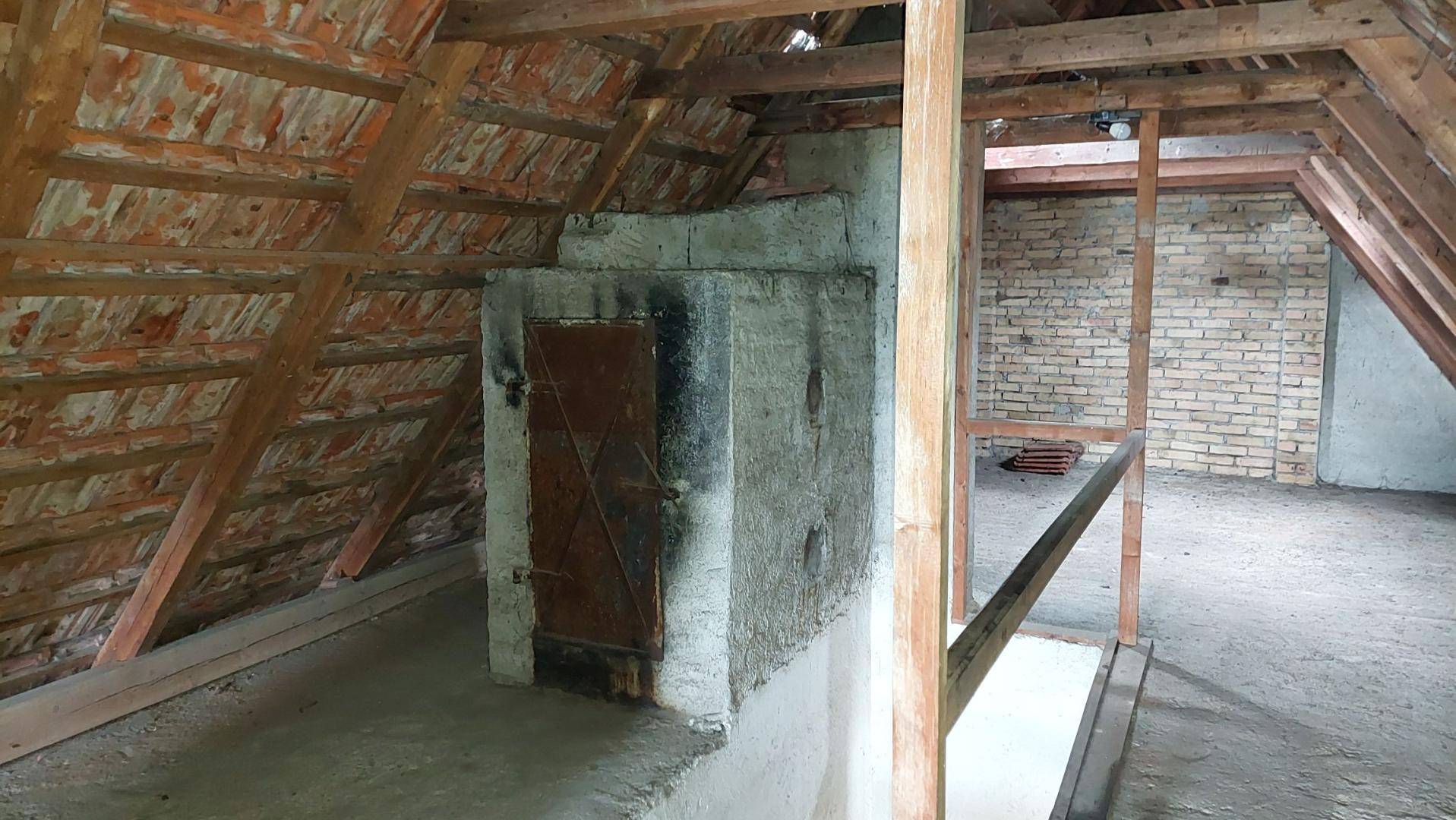 Geräumiger Dachboden mit sichtbaren Holzbalken und einem gemauerten Kaminzug, bereit für den Ausbau.