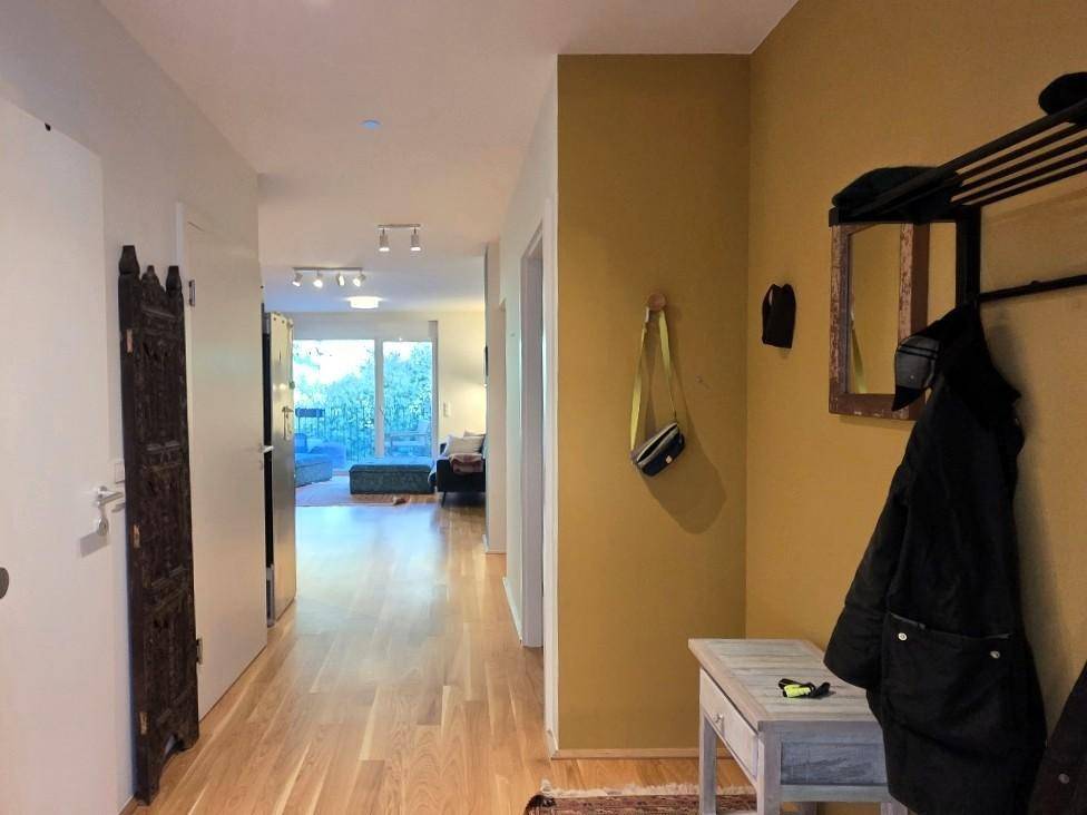 Heller Flur mit Holzboden, Garderobe und Durchblick zum Wohnbereich.
