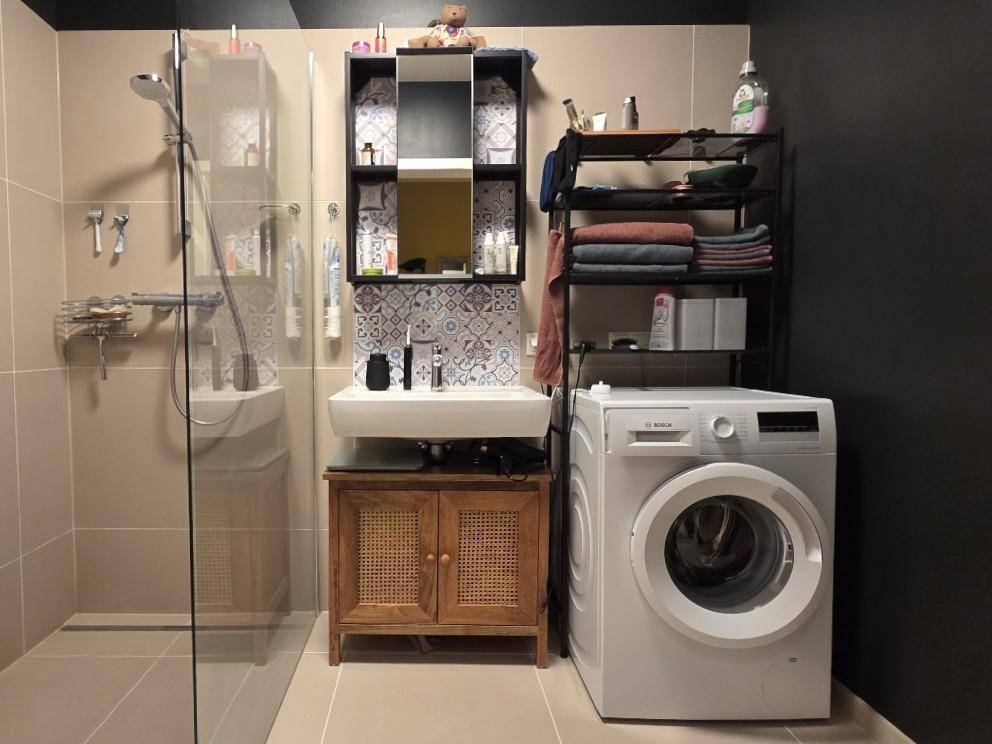 Modernes Badezimmer mit ebenerdiger Dusche, Waschbecken und Waschmaschine.