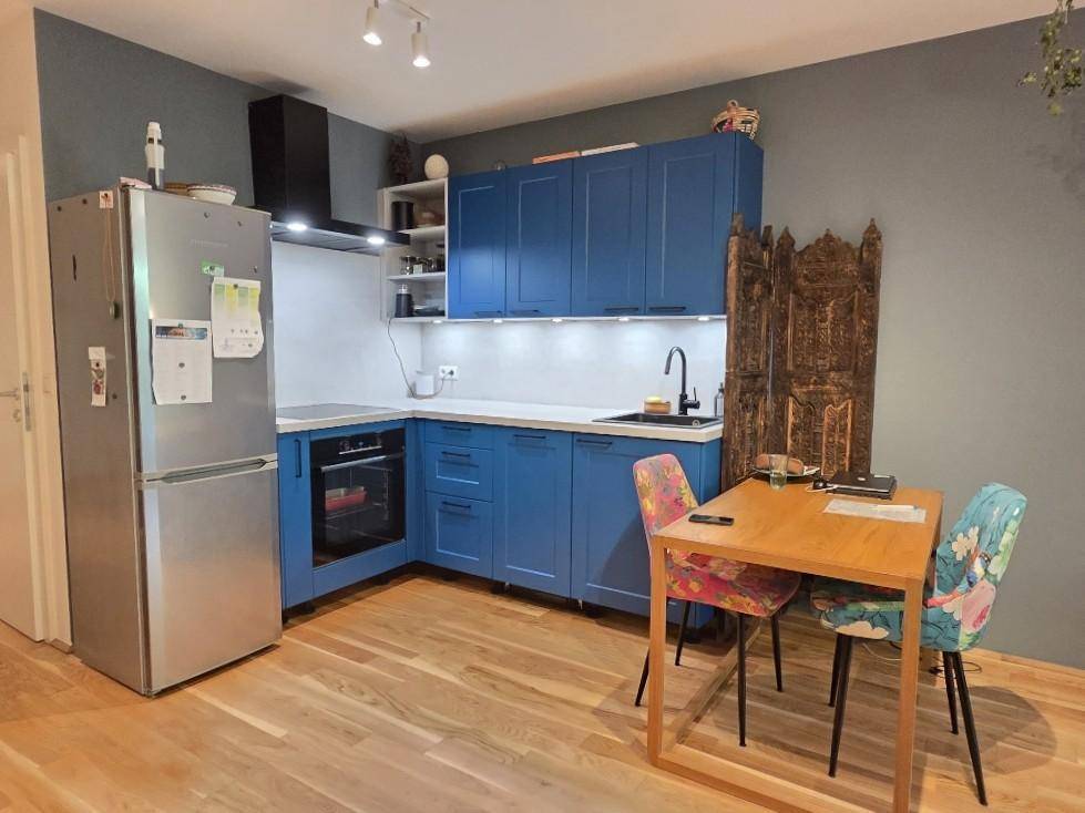 Moderne Küche mit blauen Schränken, integriertem Backofen und Essbereich.