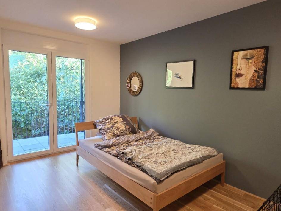 Schlafzimmer mit Einzelbett, Holzboden und direktem Zugang zum Balkon.