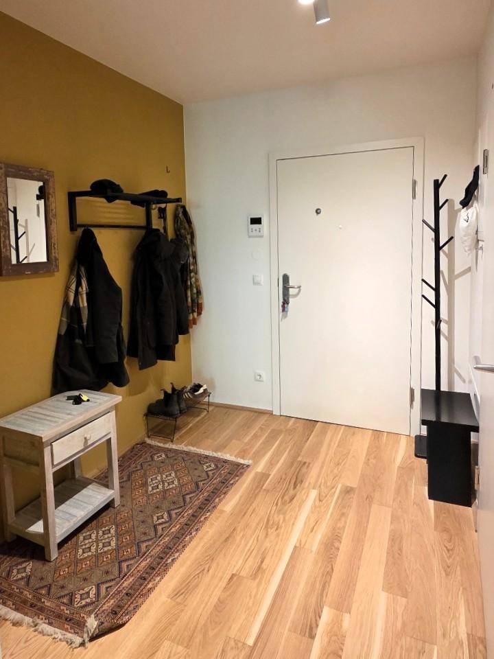 Eingangsbereich mit weißer Haustür, Garderobe und Holzboden.