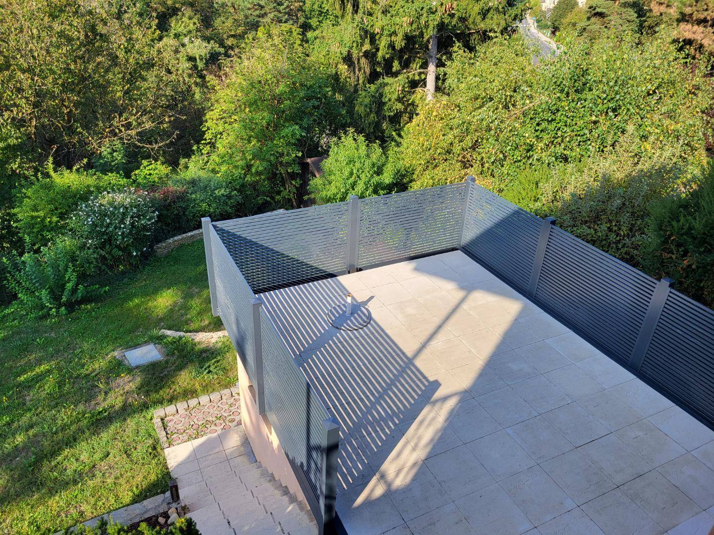 Geräumige, gepflasterte Terrasse mit Sichtschutz und Blick auf den Gartenbereich.