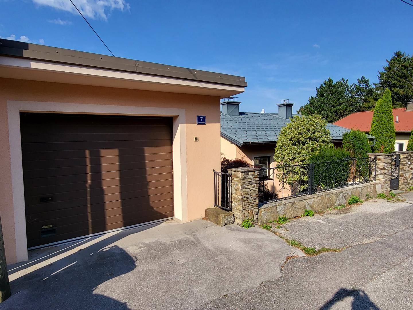 Einzelgarage mit braunem Tor und gepflasterter Zufahrt neben dem Wohnhaus.