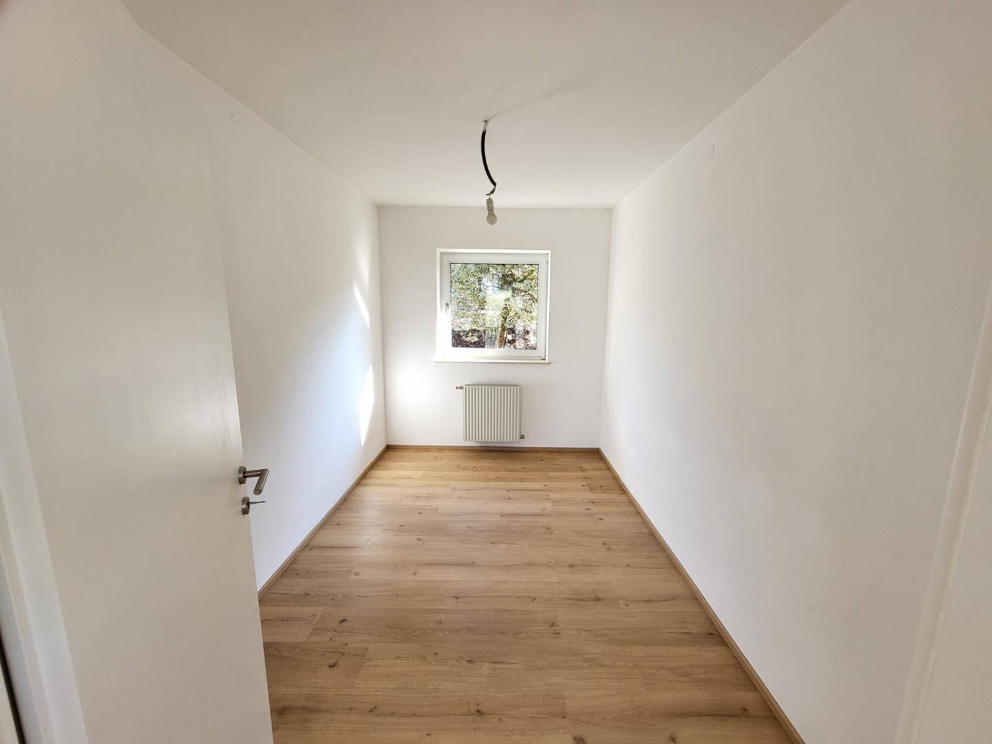 Kleines, helles Zimmer mit Laminatboden und einem Fenster, ideal als Schlaf- oder Arbeitszimmer.