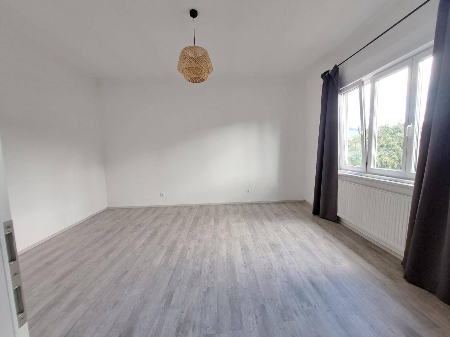 Helles Schlafzimmer mit modernem Laminatboden und großen Fenstern.