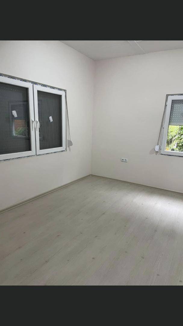 Leerer Raum mit hellem Laminatboden und zwei Fenstern, bereit zur individuellen Gestaltung.