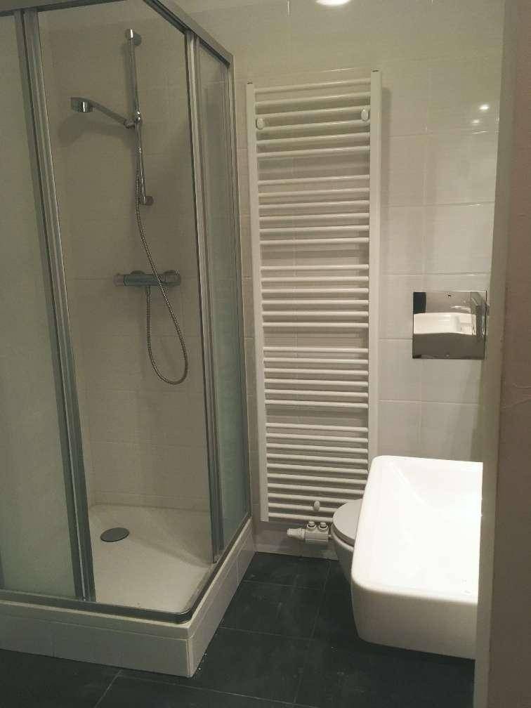 Modernes Badezimmer mit Duschkabine, WC und beheiztem Handtuchhalter.