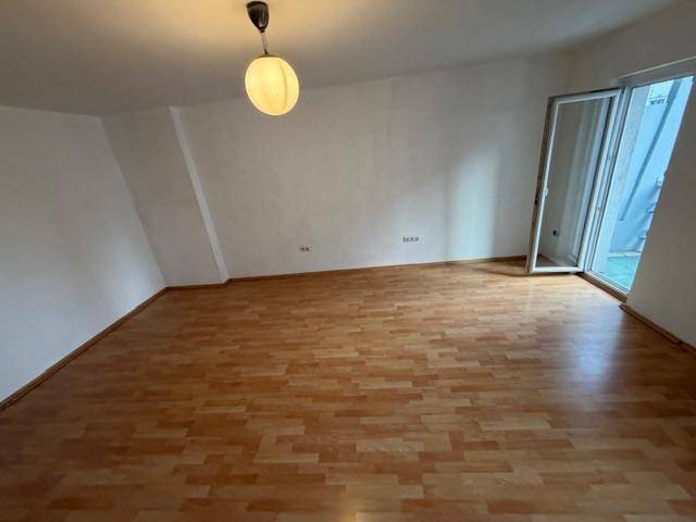 Heller, leerer Raum mit Laminatboden und Zugang zu einem Außenbereich, möglicherweise mit Dachschräge.