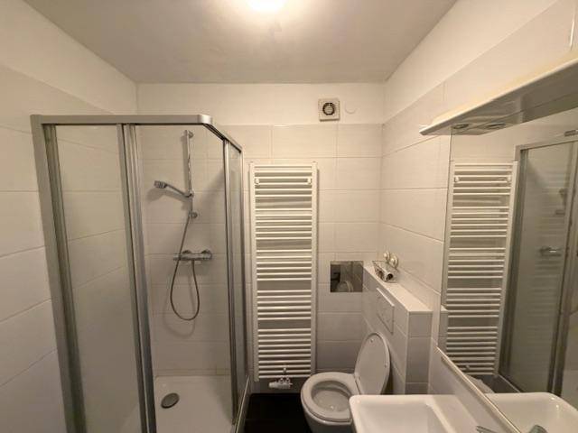 Funktionales Badezimmer mit Duschkabine, WC, Waschbecken und beheiztem Handtuchhalter.