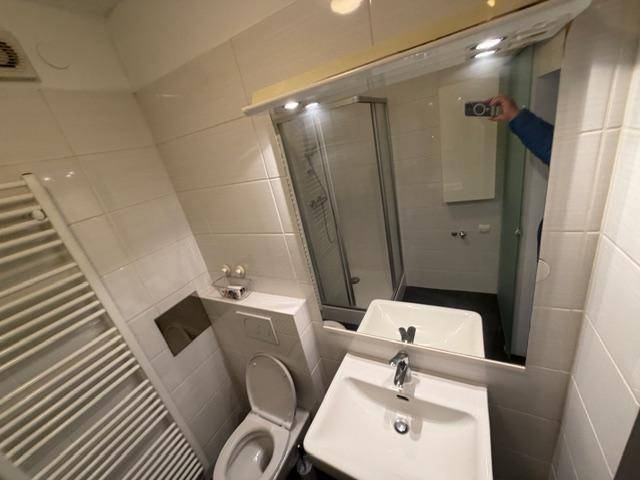 Helles Badezimmer mit Duschkabine, WC, Waschbecken und großem Spiegel.