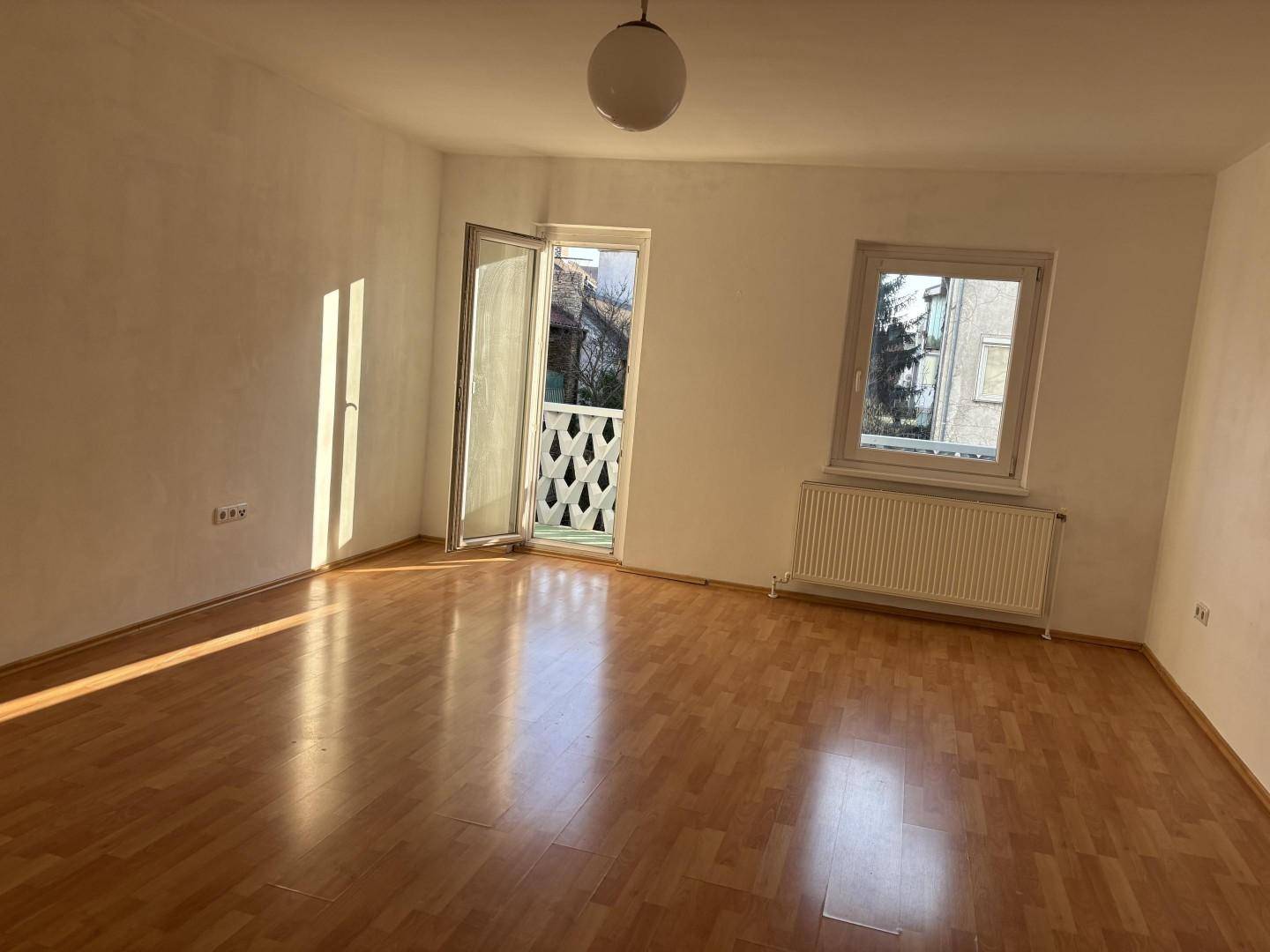 Heller Raum mit Laminatboden und Balkonzugang, ideal für individuelle Gestaltung.