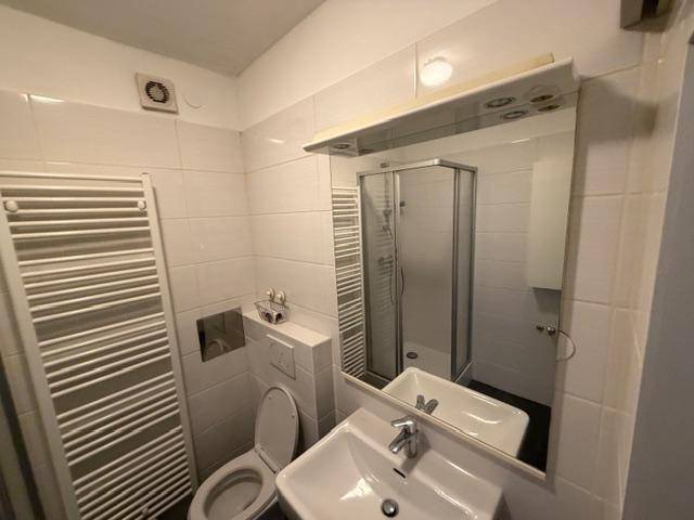 Badezimmer mit Duschkabine, WC, Waschbecken und großem Spiegel.