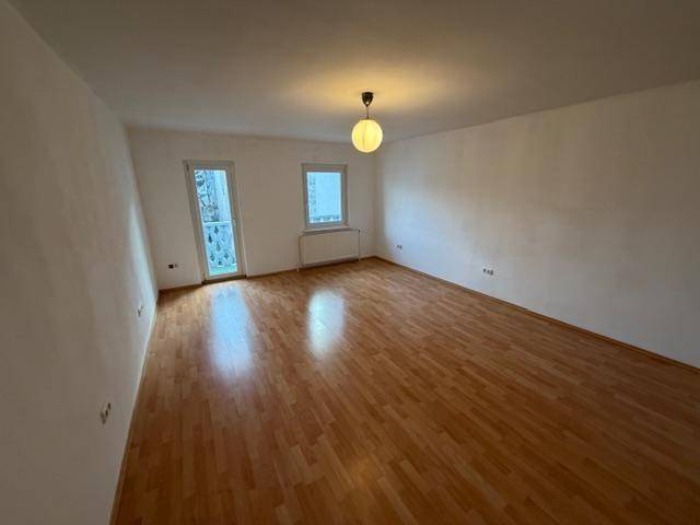 Lichtdurchfluteter Raum mit Laminatboden und Fenster, ideal für Wohn- oder Schlafzimmer.