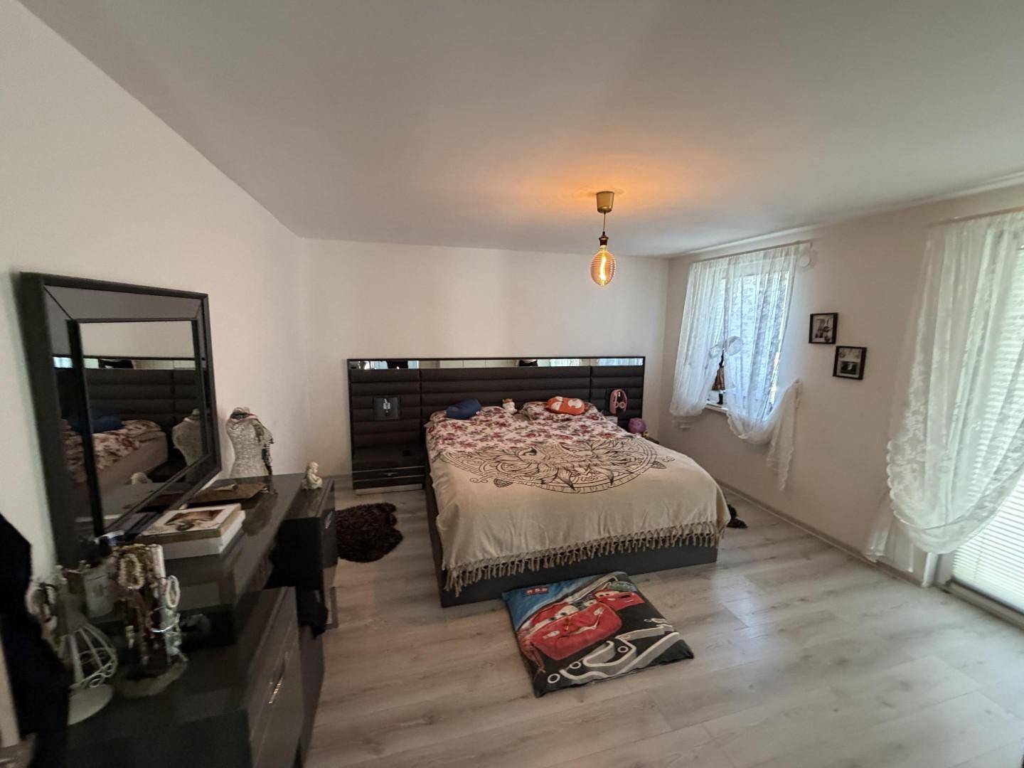 Geräumiges Schlafzimmer mit Doppelbett, Kommode und hellem Laminatboden.