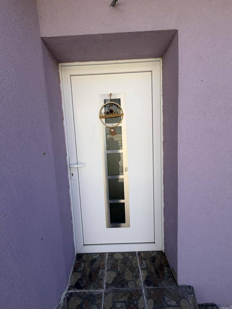 Eingangstür mit Glaselementen und einem dekorativen Kranz an der lila Fassade.