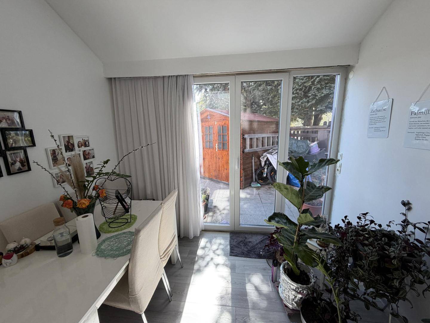 Heller Essbereich mit großem Fenster und Blick auf den Garten und das Gartenhaus.