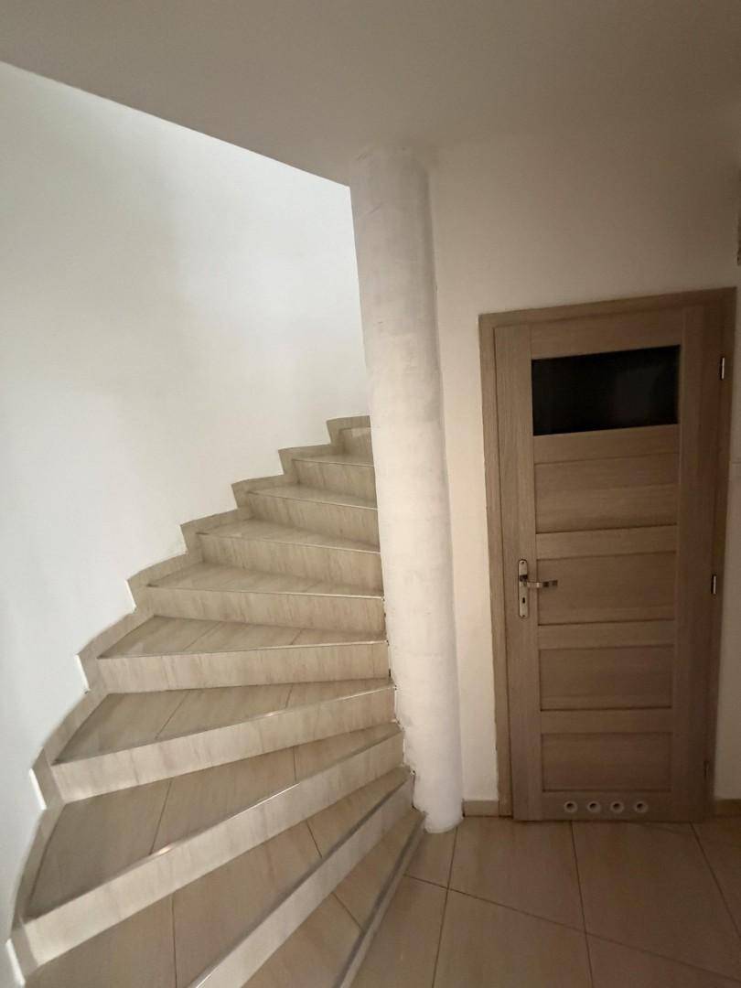 Wendeltreppe mit hellen Fliesenstufen und weißer Wand, die nach oben führt.