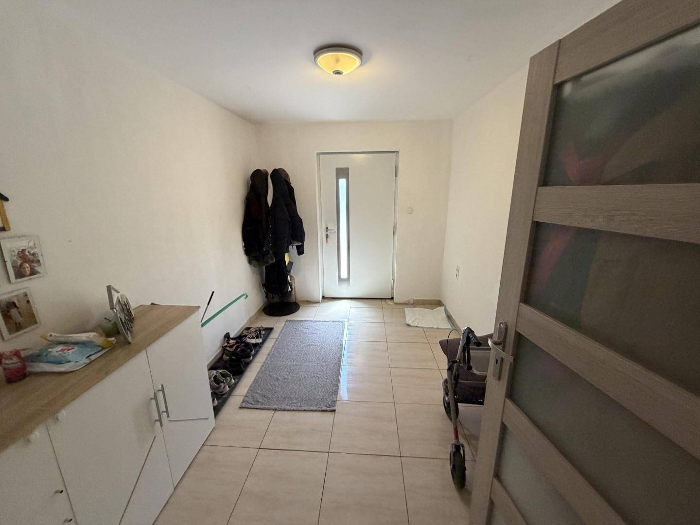 Eingangsbereich mit heller Fliesenfläche, Schuhregal und moderner Eingangstür.