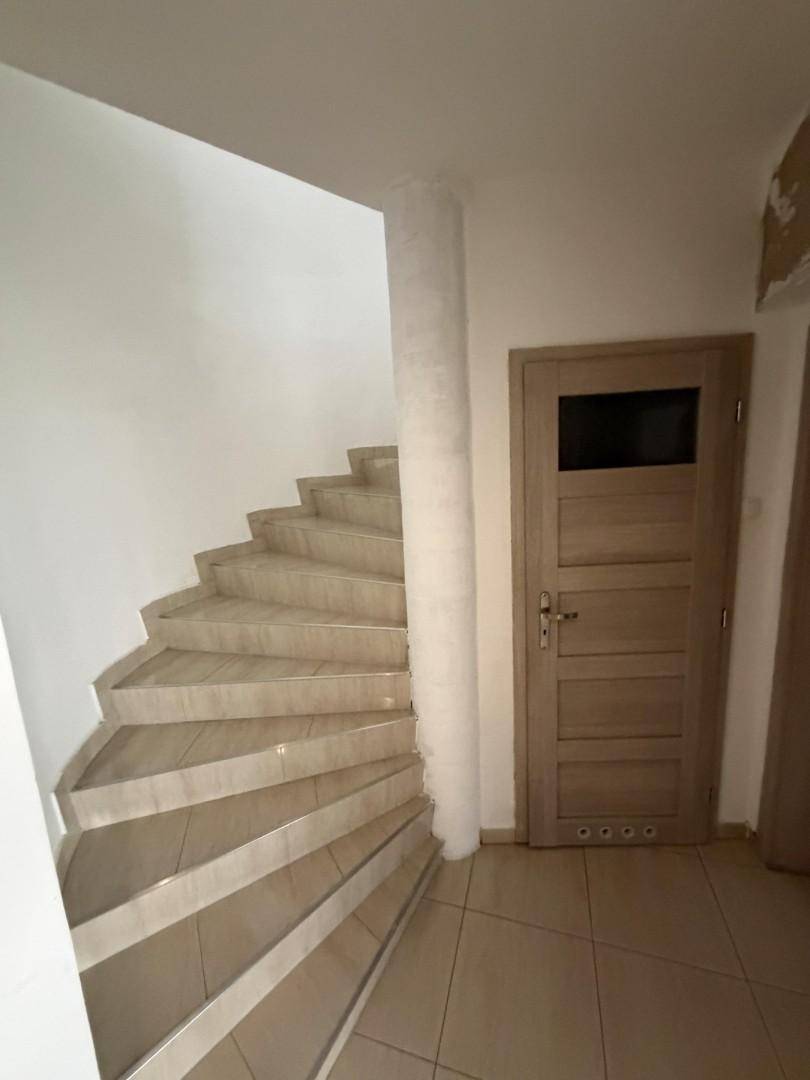 Geschwungene Treppe mit Fliesenstufen und heller Wandgestaltung.