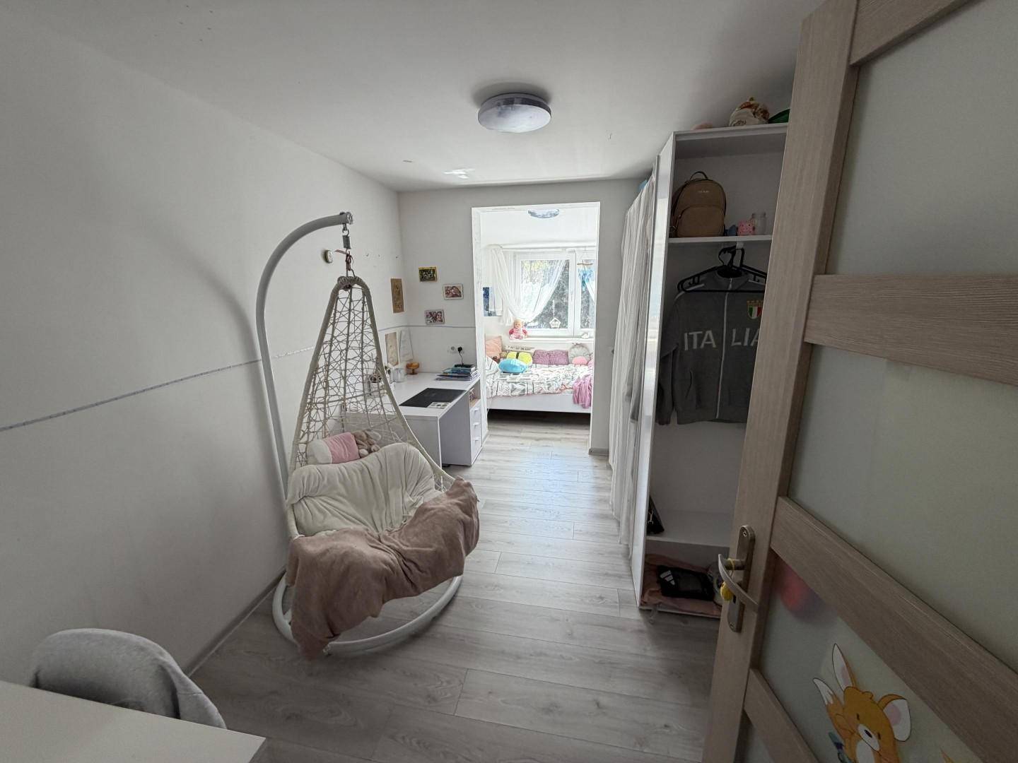 Kinderzimmer mit Schreibtisch, Hängesessel und Blick in einen weiteren Raum.
