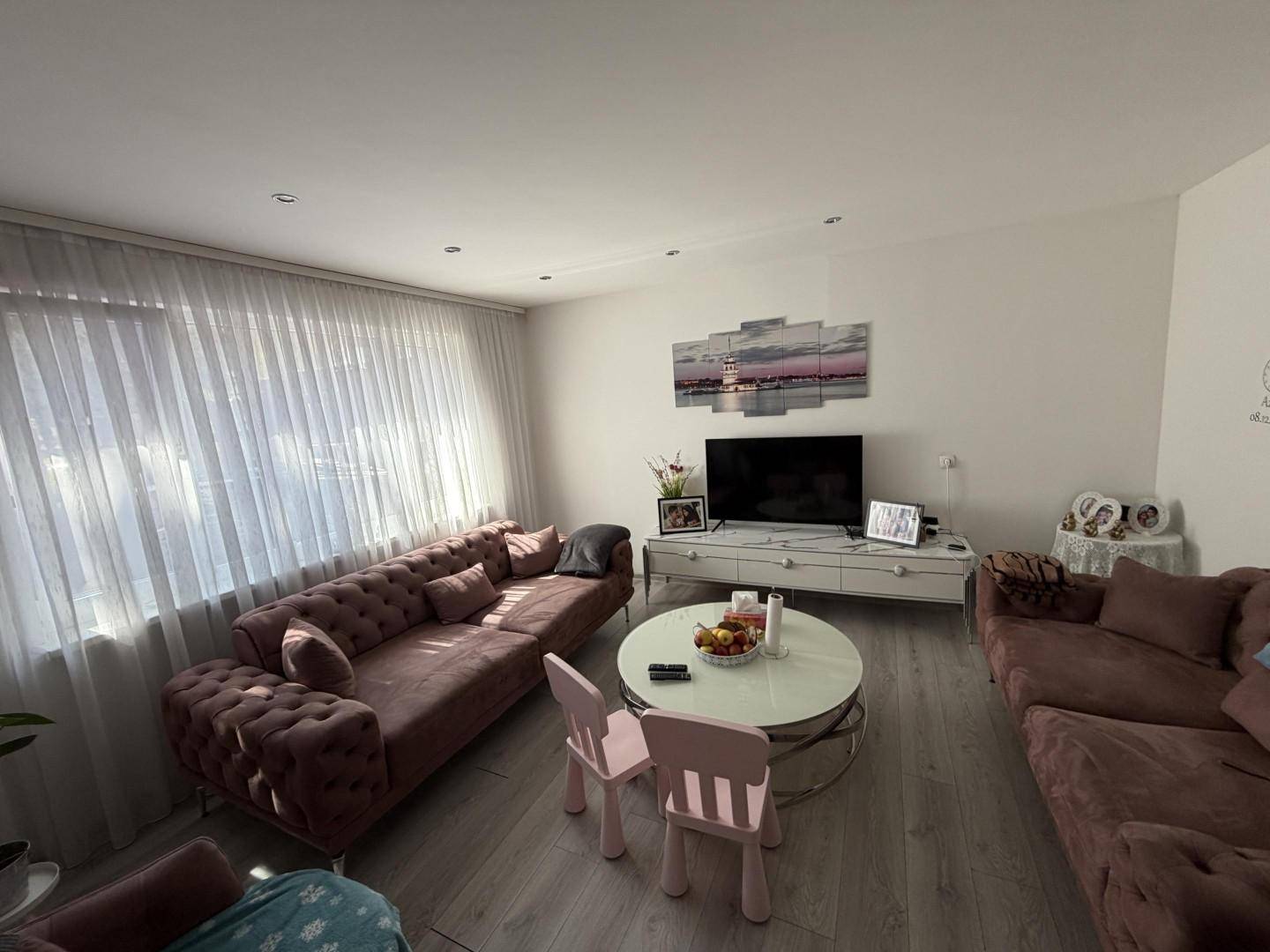 Geräumiges Wohnzimmer mit zwei Sofas, Couchtisch und viel Tageslicht.