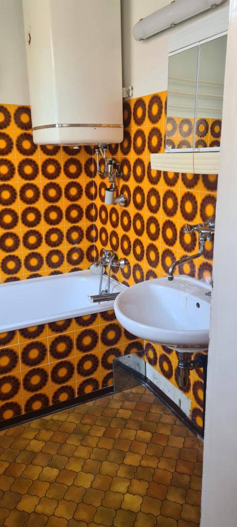 Badezimmer mit auffälligen orange-braunen Fliesen, Badewanne und Waschbecken.