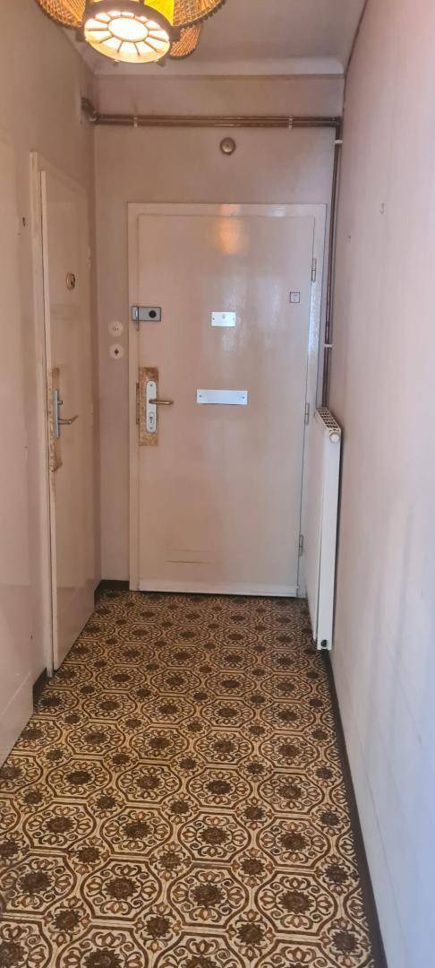 Eingangsbereich mit gemustertem Linoleumboden, Heizkörper und einer Deckenleuchte.