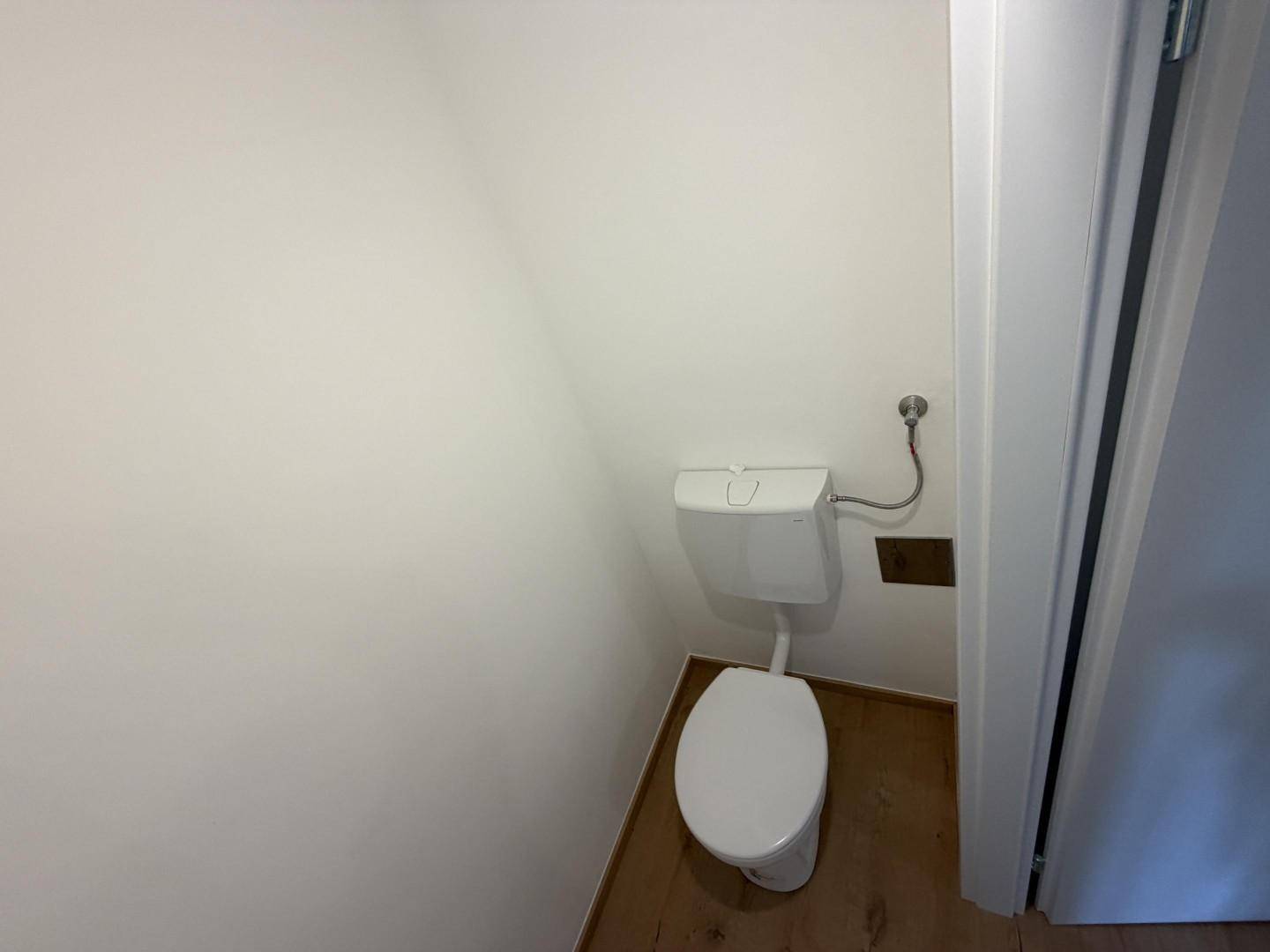 Sauberes und helles Gäste-WC mit einfacher Ausstattung und Holzboden.