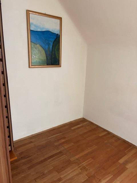 Leerer Raum mit Holzfußboden und einem gerahmten Gemälde an der Wand.