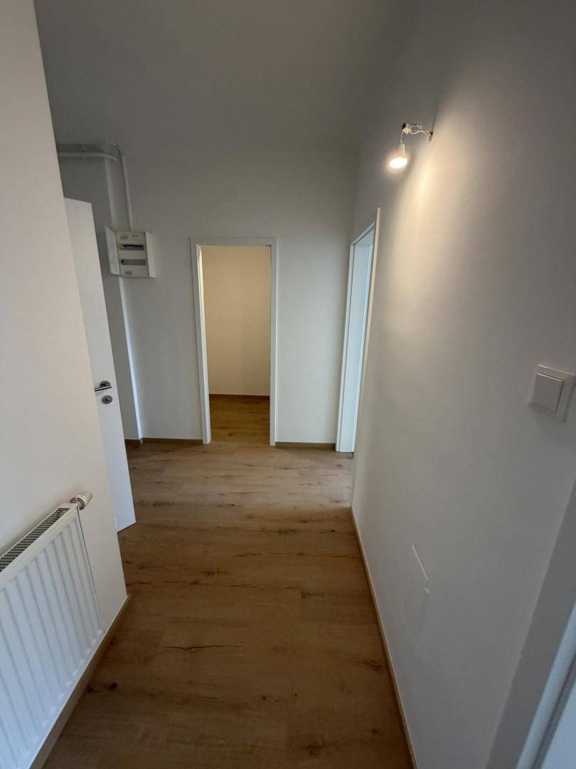 Heller Flur mit Holzboden, der zu verschiedenen Zimmern führt, ausgestattet mit Heizkörper.