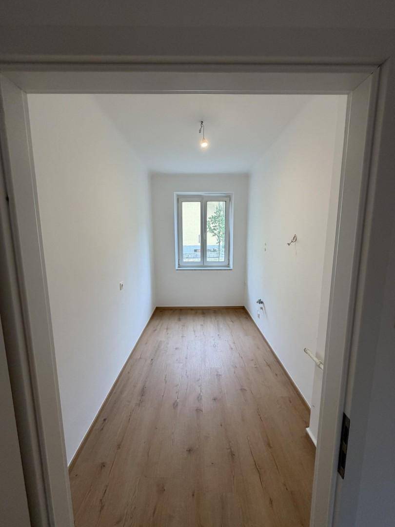 Langes, schmales Zimmer mit Holzboden und Fenster, geeignet als Schlaf- oder Arbeitszimmer.